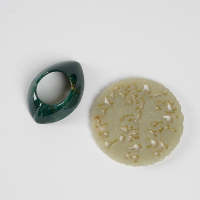 A Chinese early-middle 18C Qing dynasty small jade carved figure and an Indian early-middle 20C green jade thumb ring