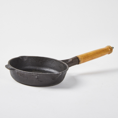 A Small Cast Iron Skillet With Wooden Handle