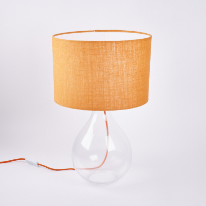 A Glass Based Table Lamp With Orange Cord And Shade