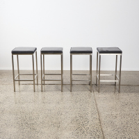 A Set of Four Stainless and Black Leather Barstools