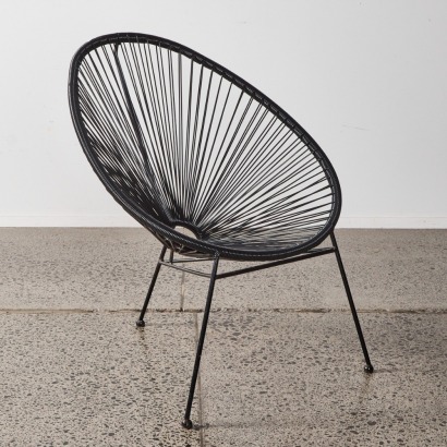 A Black Acapulco Chair In The Style Of