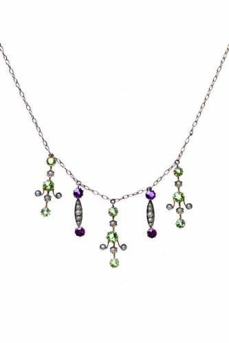 An Edwardian peridot, seed pearl and garnet pendant necklace, the front section of the fine oval link chain hung with alternating seed pearl and peridot and seed pearl and garnet drops. 9ct rose gold. Weight 4.10 grams. Length 48cm.