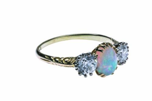 An antique opal and diamond ring, the central oval solid white opal of estimated weight 0.70 carat, shouldered by old European cut diamonds of estimated total weight 1.25 carats. Engraved detail to shoulders. 18ct yellow gold. Weight 3.21 grams. Size R.&nbsp;