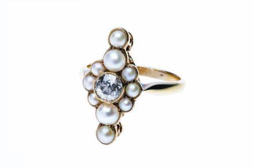 An antique style pearl and diamond ring, the bezel set old brilliant cut diamond surrounded by half pearls. 18ct yellow gold. Weight 3.55 grams. Size K.