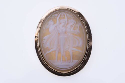 A cameo brooch, the oval helmet shell cameo depicting the three graces. 9ct yellow gold. Weight 8.43 grams. Length 40mm.