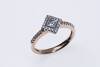 A diamond ring, the central princess cut diamond in an offset square diamond set mount with diamond line shoulders. 9ct rose gold. Weight 2.74 grams. Size N&frac12;..