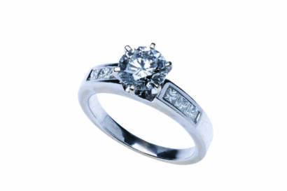 A solitaire diamond ring, six claw set with a round brilliant cut diamond of estimated weight 1.10 carats, and shouldered by six channel set princess cut diamonds of estimated total weight 0.30 carat. 18ct white gold. Weight 4.27 grams. Size I½.