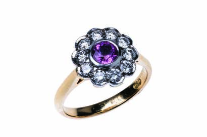 A sapphire and diamond cluster ring, the central pink sapphire of estimated weight 0.60 carat, surrounded by ten round brilliant cut diamonds of total estimated weight 0.59 carat. 18ct yellow gold. Weight 4.6 grams. Size M.