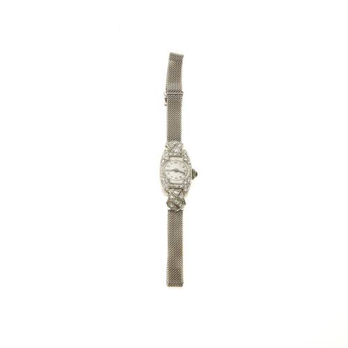 A Lady's gold, platinum and diamond cocktail watch, circa 1930's. Manual. Barrel-shaped case with white dial and painted black Arabic numerals. Diamond set bezel and shield-shaped lugs. Blue cabochon sapphire set crown. Unsigned Swiss movement. 9ct white 