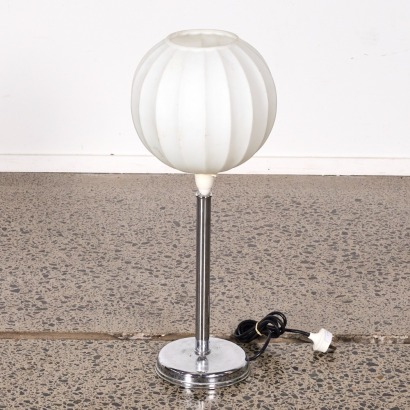 A Chrome Lamp With A Glass White Top