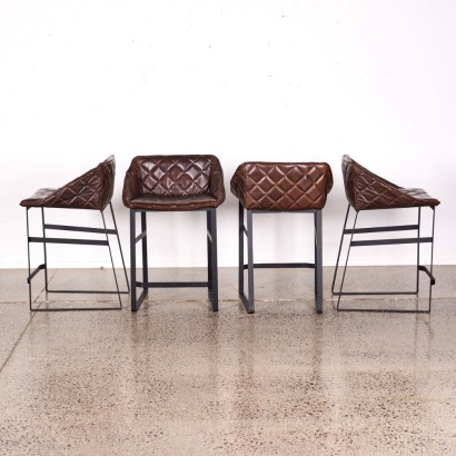 A Suite of Four Brown Padded Leather Bar Stools with Black Metal Base