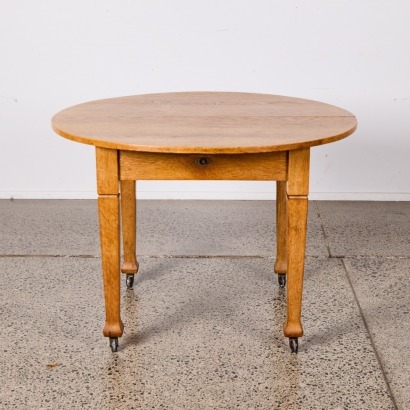 An Antique Round Extendable Blond Oak Dining Table With Crank And Two Extension Leaves